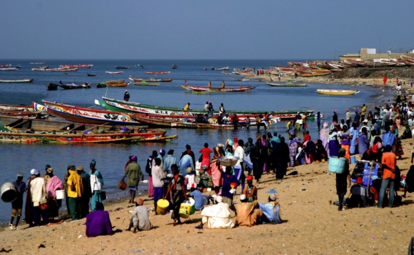 Fishing boats in the water and people on the shore, on a beach in Senegal