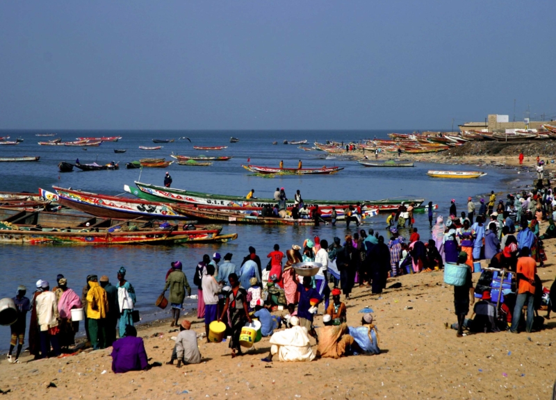 Fishing boats in the water and people on the shore, on a beach in Senegal