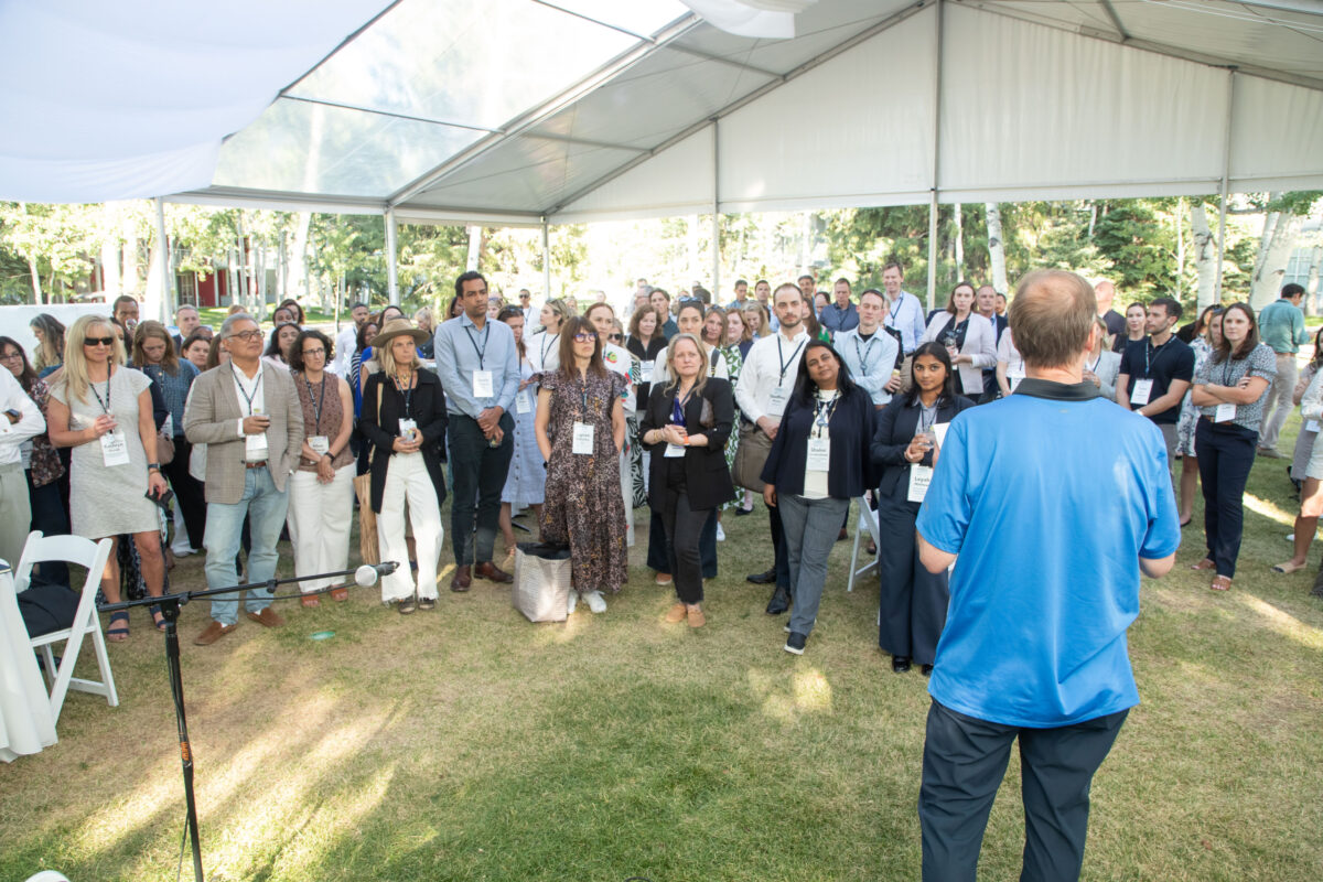 Participants at the Aspen Institute Business and Society Summit gathered on a lawn to listen to a speaker