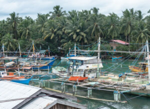 A fishing village in the Philippines, with multiple boats at the dock and small houses on stilts