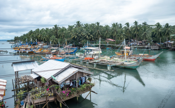 A fishing village in the Philippines, with multiple boats at the dock and small houses on stilts