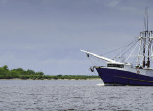A shrimp boat passes the historic Sabine Pass Lighthouse