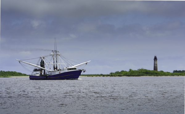 A shrimp boat passes the historic Sabine Pass Lighthouse