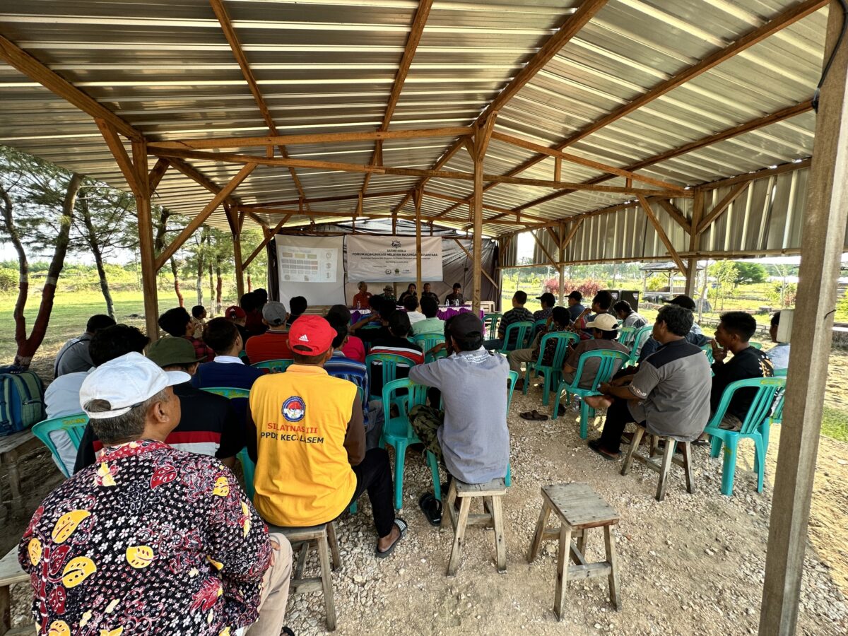 The members of the BSC fishers network, sitting under an open-air shelter at t a meeting, as seen from behind
