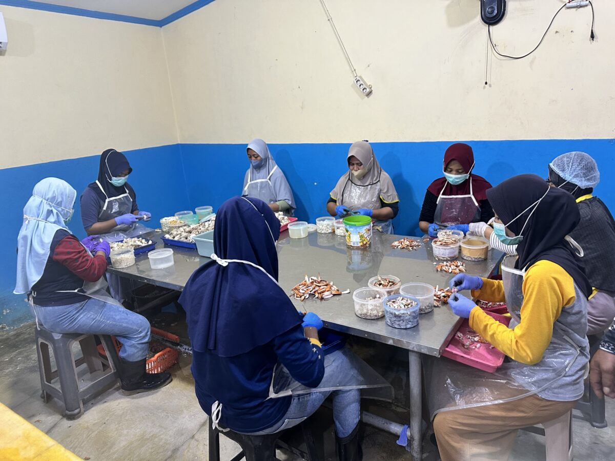 Women sitting around a table picking crab meat out of crabs