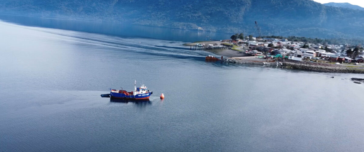 A fishing boat sailing toward a small town
