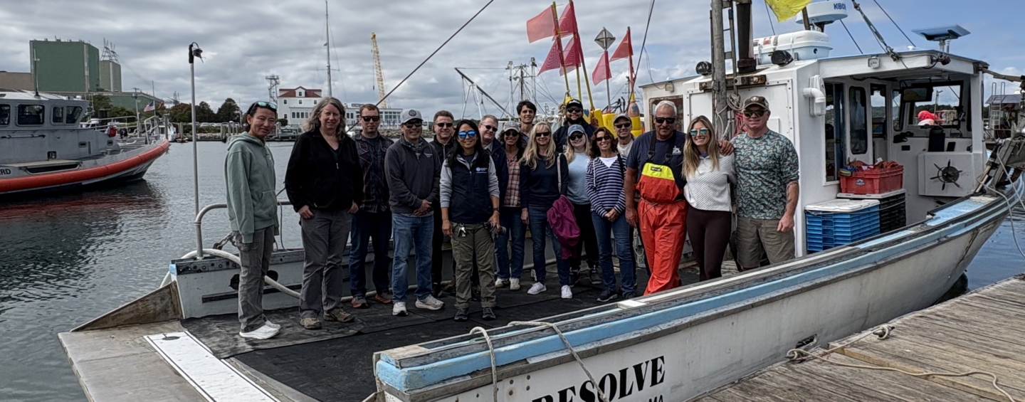A group of people posing on a lobster boat in Cape Cod Bay