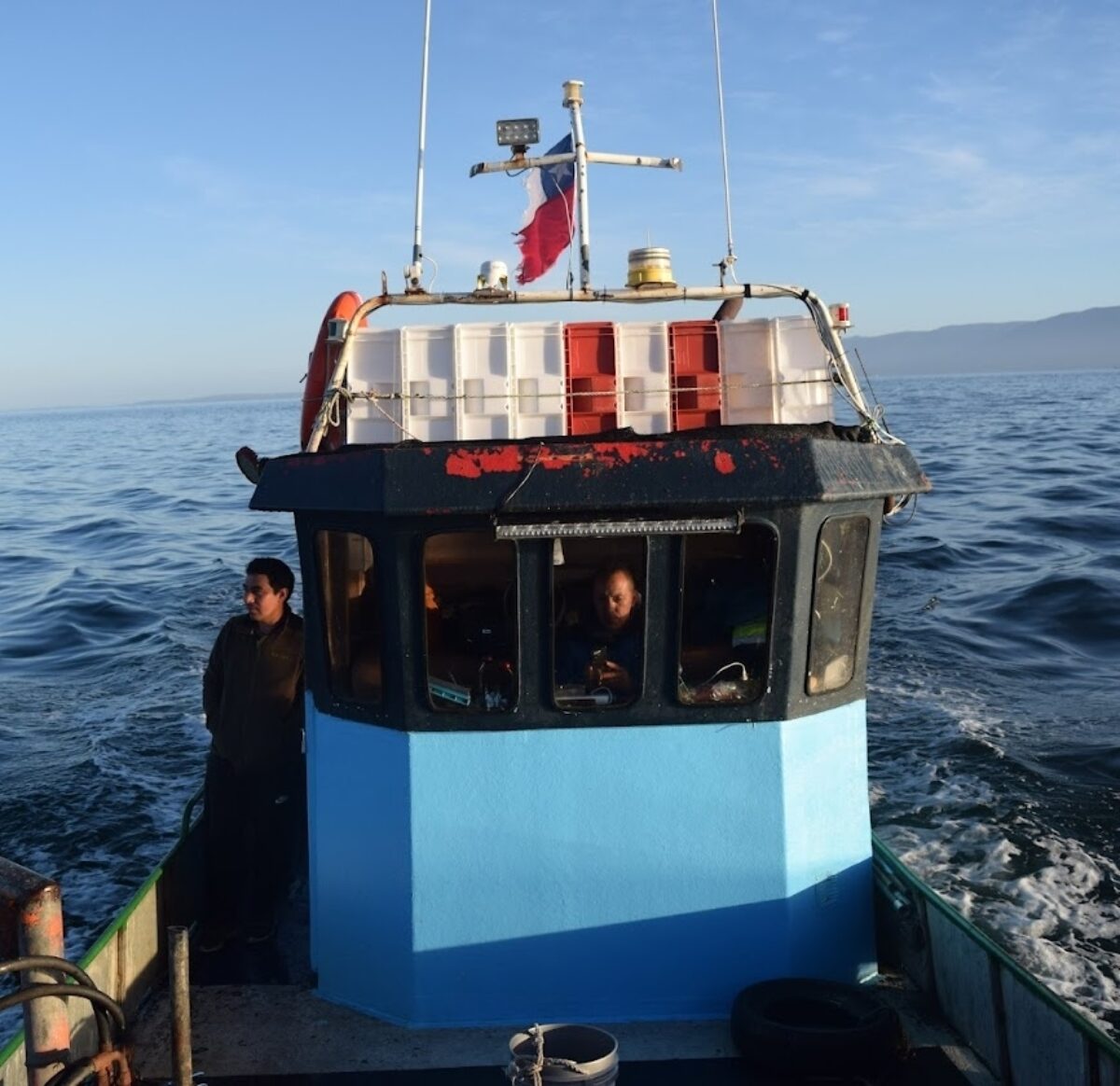 several fisherman standing on the deck of a blue boat