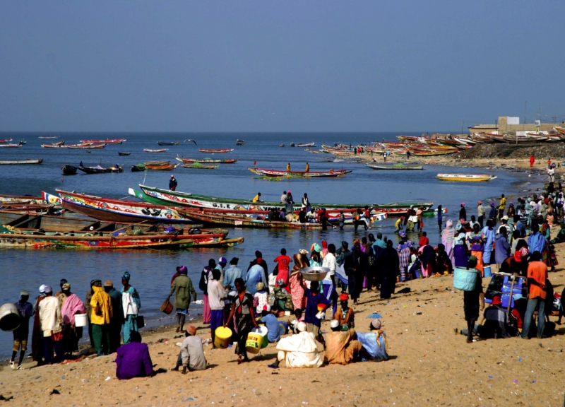 Fishing boats in the water and people on the shore, on a beach in Senegal