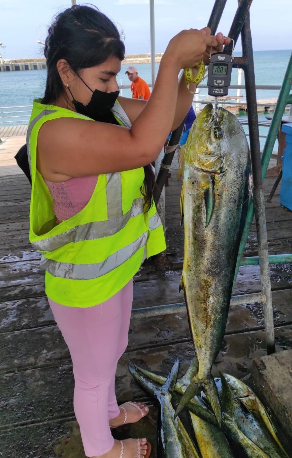 A woman weighing a large mahi fish