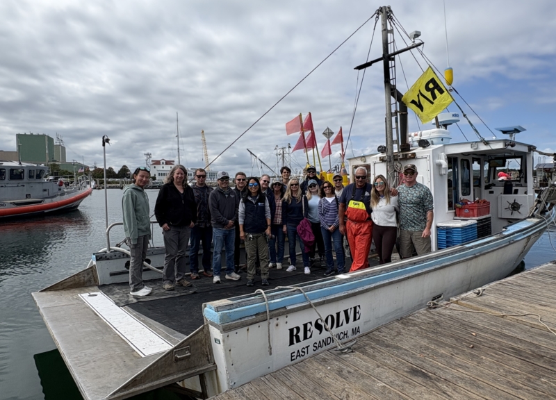 A group of people posing on a lobster boat in Cape Cod Bay
