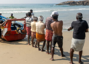 Un groupe de pêcheurs tirant un bateau en bois vers le rivage