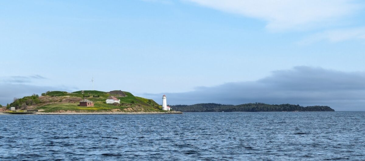 Scene of a lighthouse and distant shore from the ocean in Halifax, Canada
