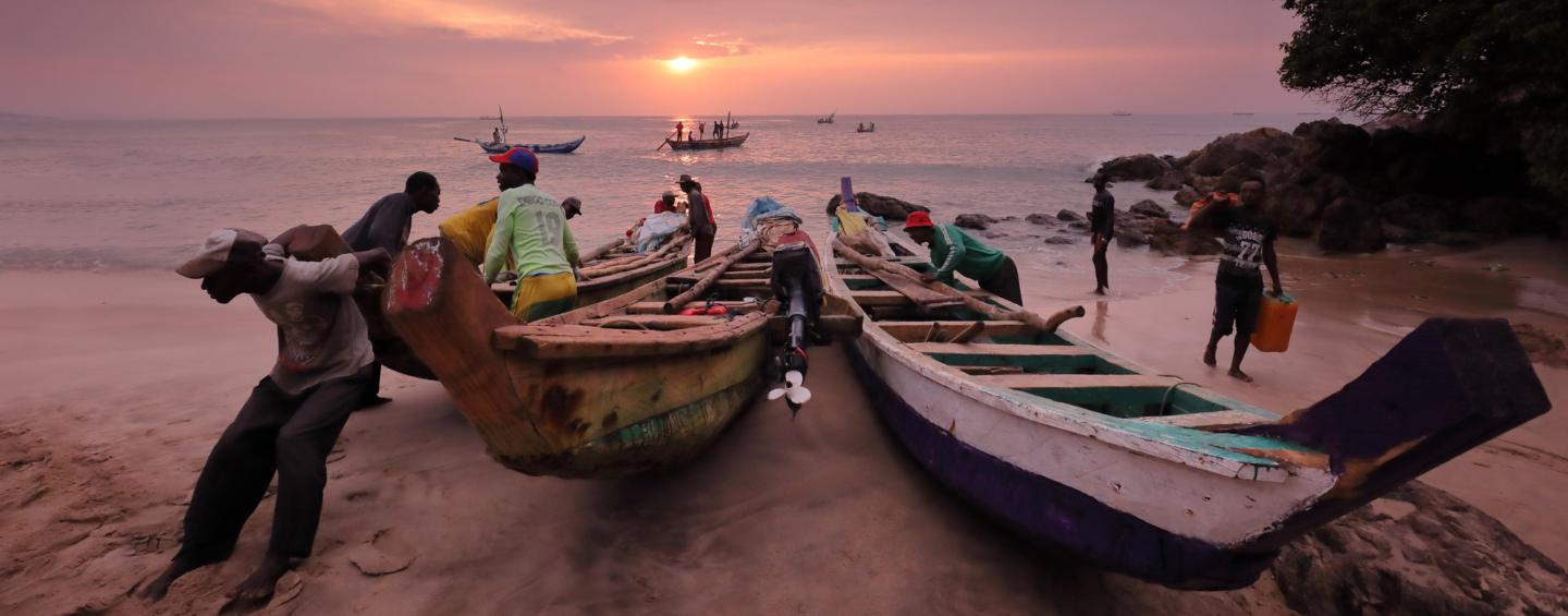 Fishers launching a boat at sunrise, Ghana