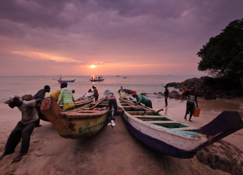 Fishers launching a boat at sunrise, Ghana