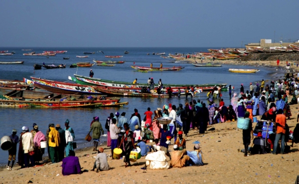 Fishing boats in the water and people on the shore, on a beach in Senegal