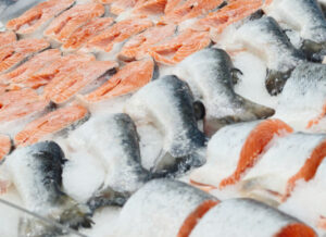 Mostrador de pescado de un supermercado con una variedad de cortes de salmón expuestos sobre hielo